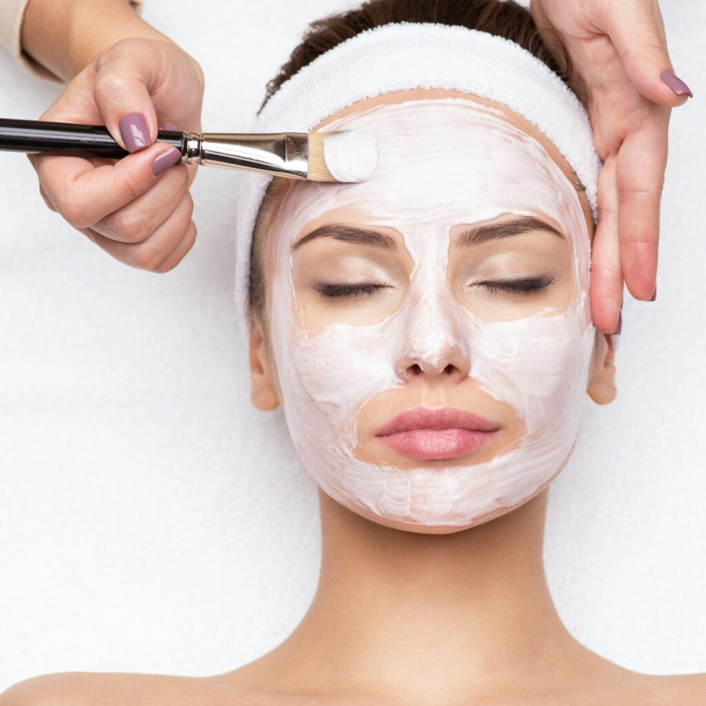 Woman receiving facial mask at beauty salon